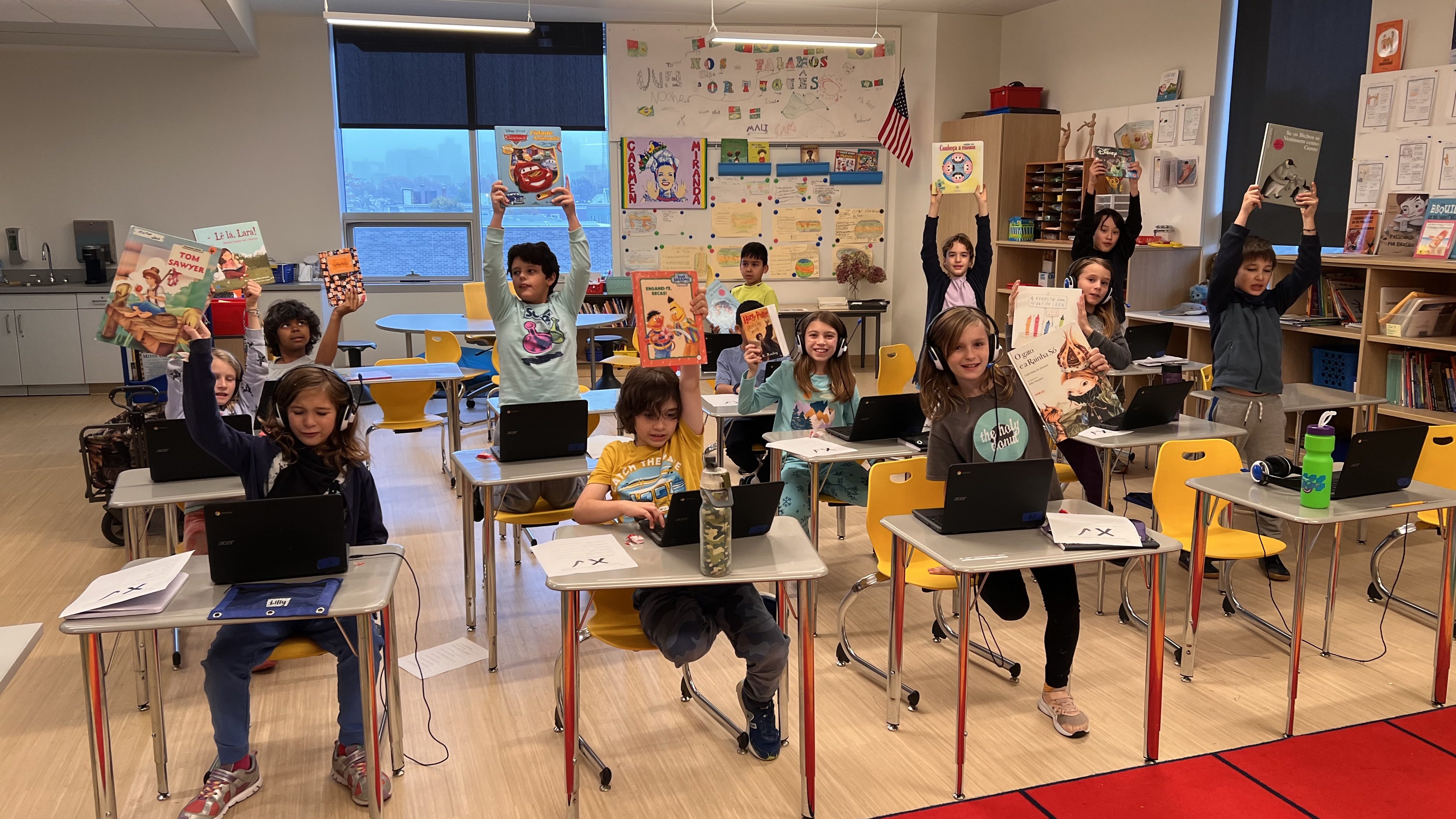Ola 5th graders in their classroom holding up Portuguese picture books 